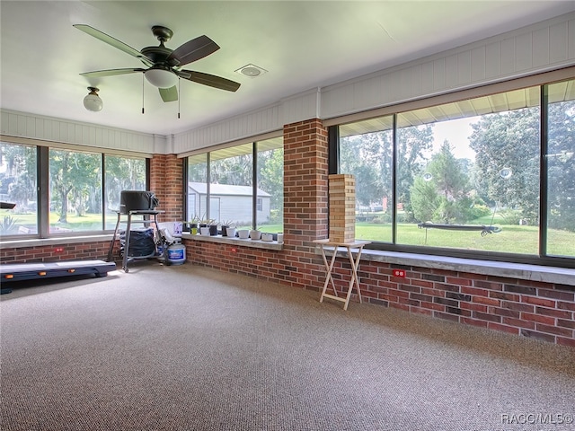 misc room featuring carpet flooring, ceiling fan, and brick wall