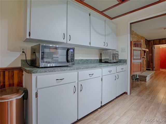 kitchen featuring light hardwood / wood-style flooring, white cabinetry, and wood walls