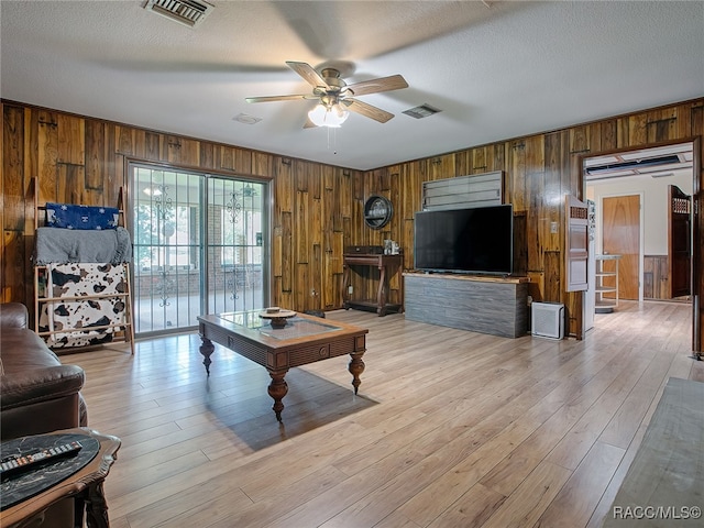 living room with a textured ceiling, light wood-type flooring, and ceiling fan