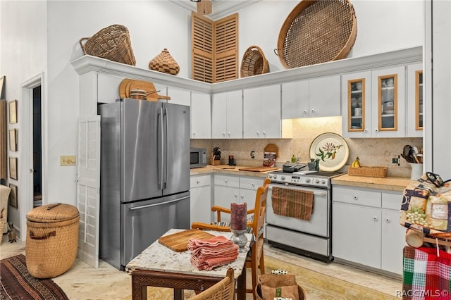 kitchen featuring white cabinets, crown molding, decorative backsplash, appliances with stainless steel finishes, and light hardwood / wood-style floors