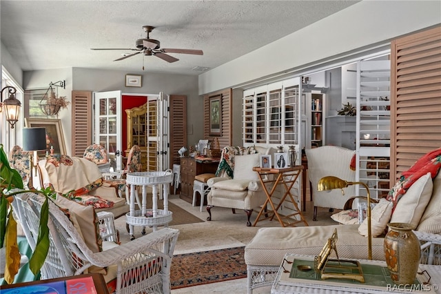 carpeted living room featuring ceiling fan and a textured ceiling