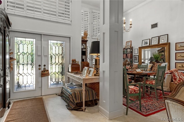 entrance foyer with crown molding, plenty of natural light, a towering ceiling, and french doors