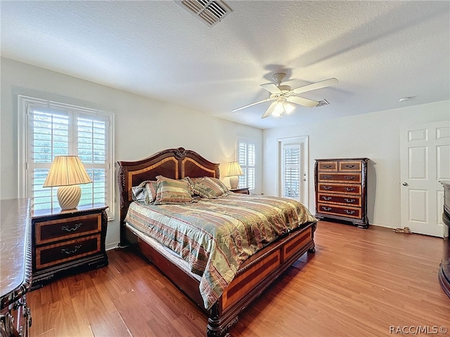 bedroom featuring hardwood / wood-style floors, ceiling fan, and a textured ceiling