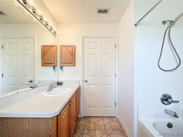 bathroom with vanity, a textured ceiling, and tub / shower combination