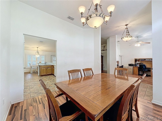 dining room with light hardwood / wood-style flooring, ceiling fan with notable chandelier, and sink