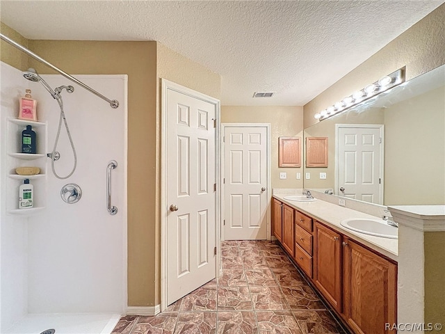 bathroom with vanity, a textured ceiling, and walk in shower