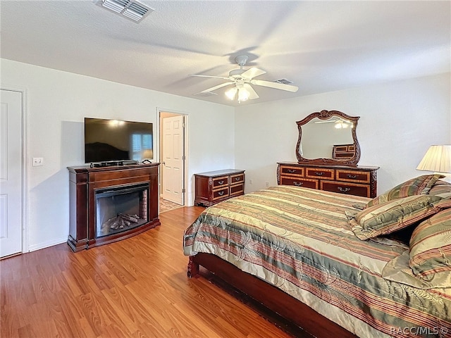 bedroom featuring wood-type flooring, a textured ceiling, and ceiling fan