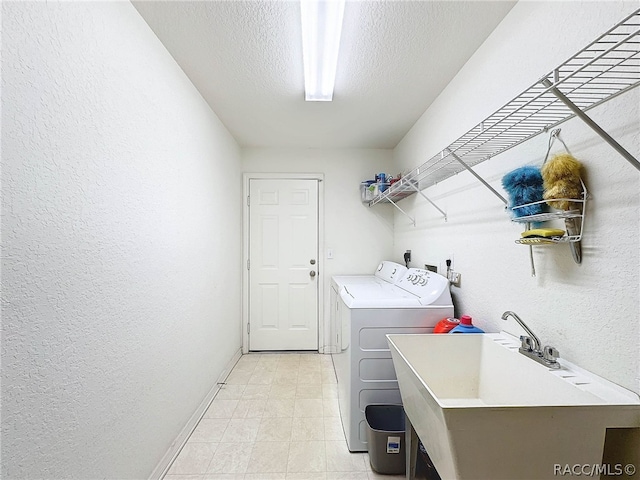 laundry area with a textured ceiling, separate washer and dryer, and sink