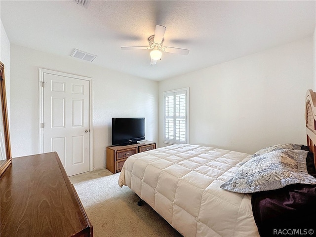 bedroom with light carpet, a textured ceiling, and ceiling fan