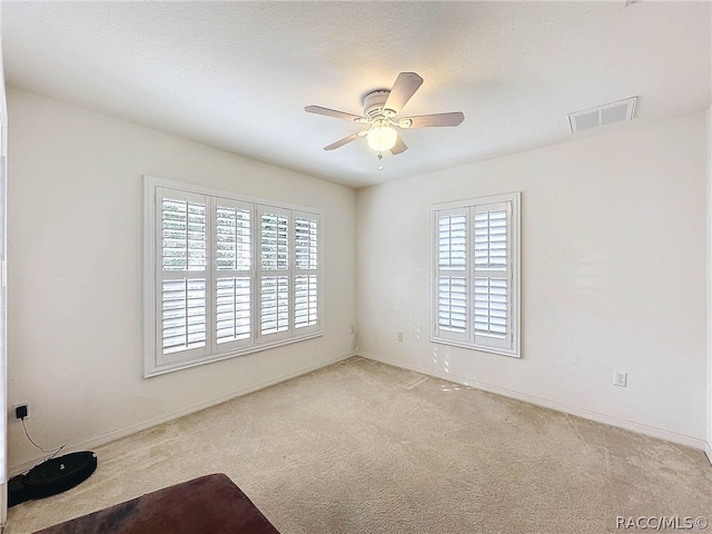 carpeted empty room with ceiling fan and a textured ceiling