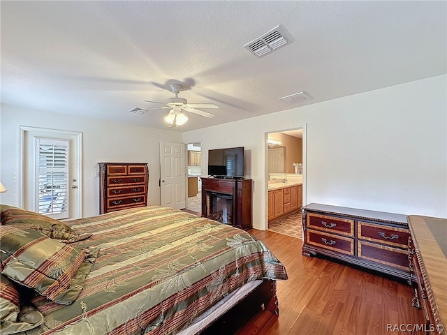 bedroom with ceiling fan, access to exterior, light wood-type flooring, a textured ceiling, and connected bathroom