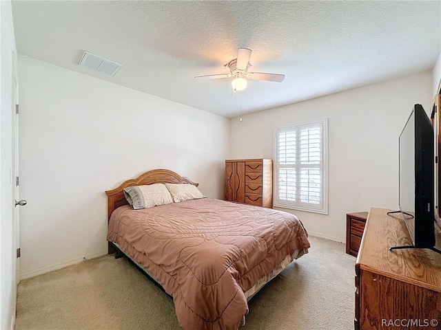 carpeted bedroom with ceiling fan and a textured ceiling