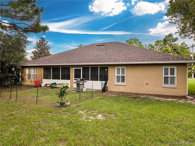 rear view of property featuring a yard and a sunroom