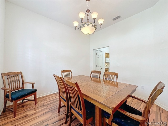 dining area with light hardwood / wood-style floors and an inviting chandelier