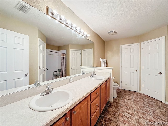 bathroom featuring vanity, a textured ceiling, and toilet