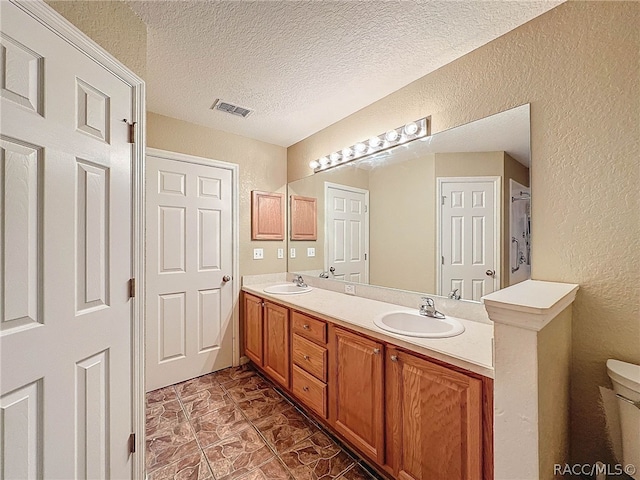 bathroom featuring vanity, a textured ceiling, and toilet