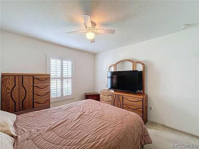 carpeted bedroom with ceiling fan and a textured ceiling