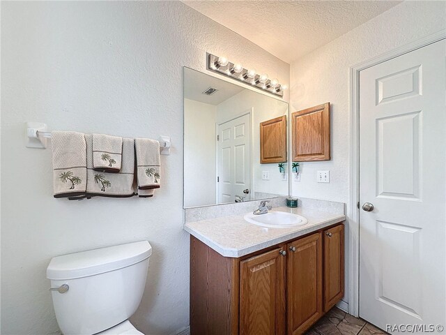 bathroom with vanity, a textured ceiling, and toilet