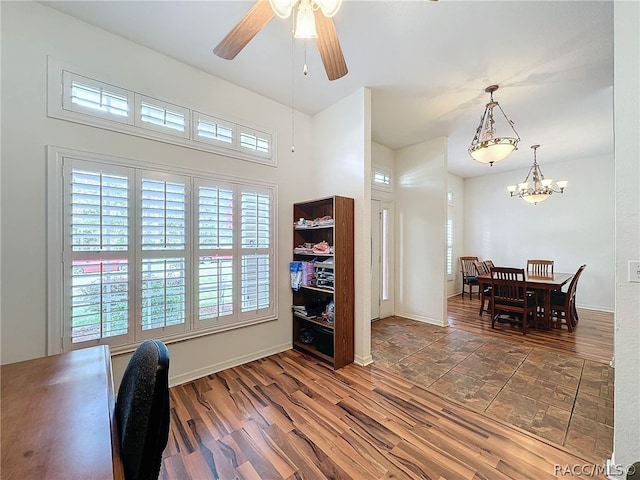 office space with ceiling fan with notable chandelier and dark hardwood / wood-style flooring