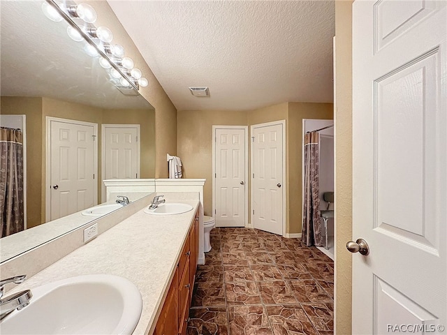 bathroom featuring vanity, a textured ceiling, toilet, and curtained shower