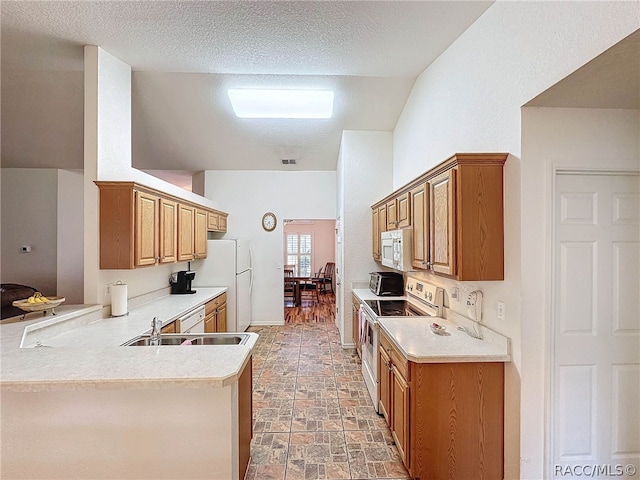 kitchen featuring sink, kitchen peninsula, a textured ceiling, lofted ceiling, and white appliances