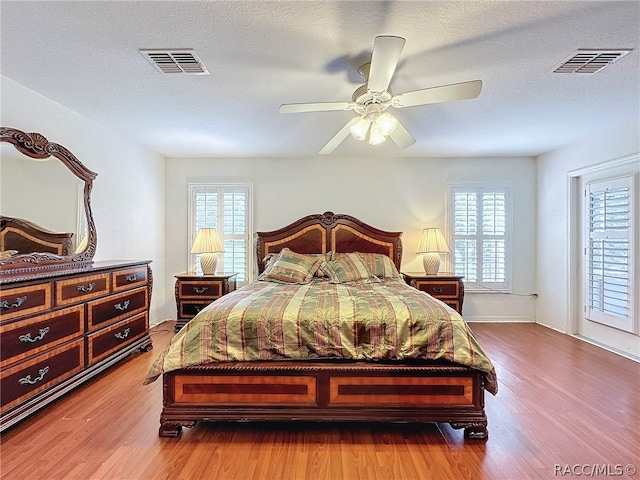 bedroom with multiple windows, ceiling fan, and light hardwood / wood-style flooring