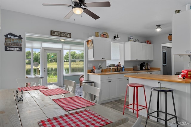 4306 E Gloria Dr, Hernando, FL 34442 - kitchen with light wood-type flooring, white cabinets, a breakfast bar, a ceiling fan, and butcher block countertops
