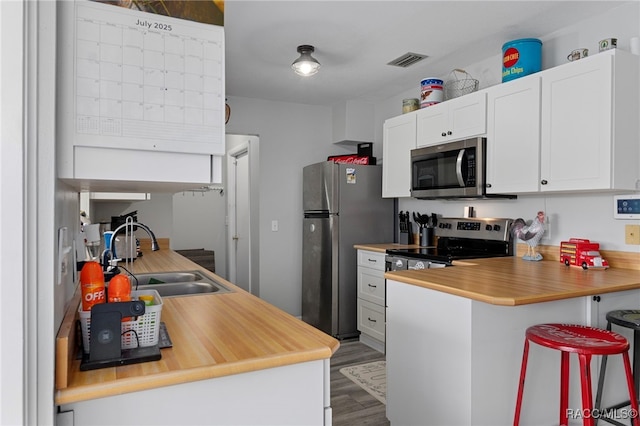 4306 E Gloria Dr, Hernando, FL 34442 - kitchen with stainless steel appliances, a peninsula, dark wood finished floors, white cabinetry, and a breakfast bar area