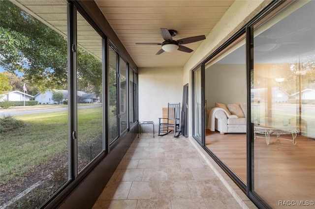 unfurnished sunroom with ceiling fan