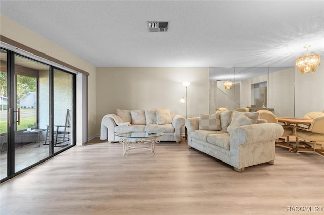 living room with a textured ceiling, light hardwood / wood-style floors, and a notable chandelier