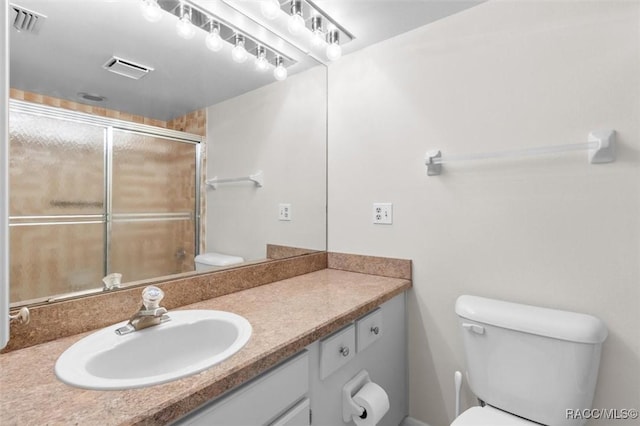 bathroom with vanity, toilet, and a shower with shower door