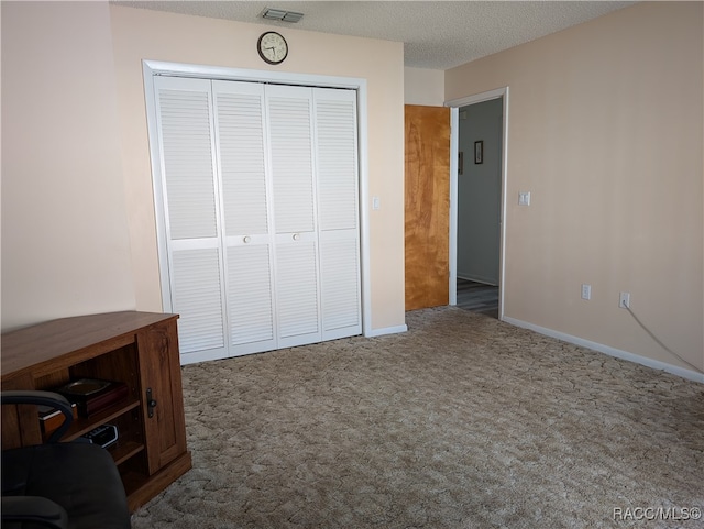 unfurnished bedroom with a textured ceiling, dark carpet, and a closet