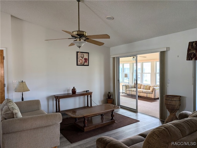 living room featuring ceiling fan, a textured ceiling, and light wood-type flooring