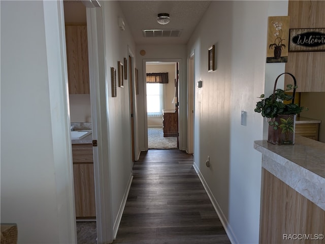 corridor with dark hardwood / wood-style flooring and a textured ceiling