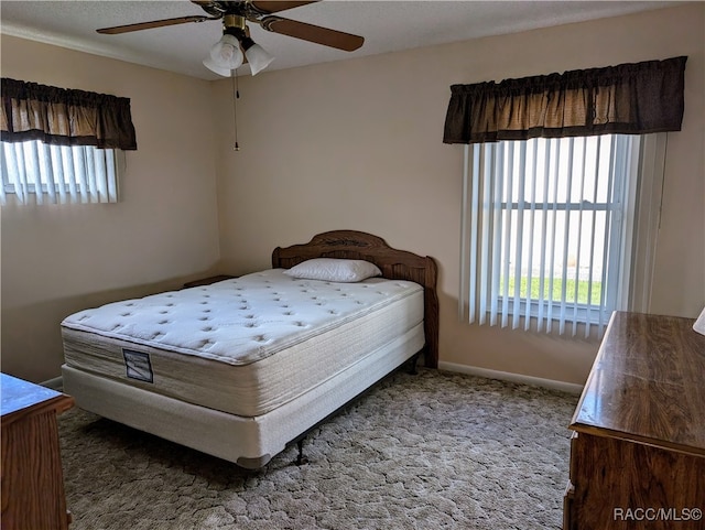 carpeted bedroom featuring multiple windows and ceiling fan