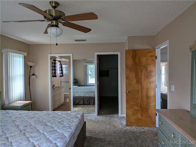 carpeted bedroom featuring ensuite bathroom, ceiling fan, a spacious closet, a textured ceiling, and a closet