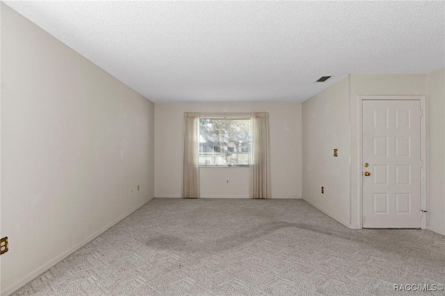 empty room with a textured ceiling and light carpet