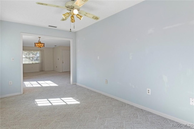 carpeted spare room with ceiling fan with notable chandelier