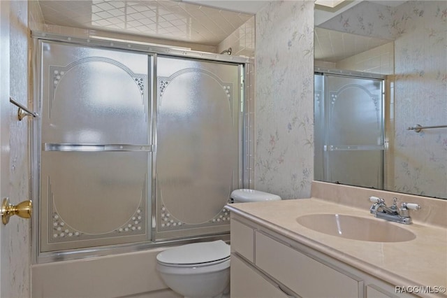 full bathroom with bath / shower combo with glass door, vanity, and toilet