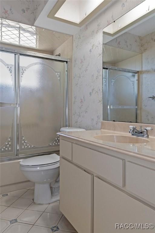 full bathroom featuring enclosed tub / shower combo, vanity, toilet, and tile patterned flooring