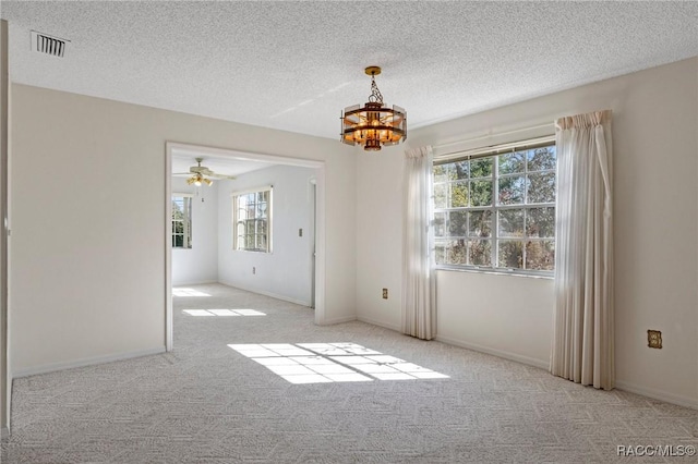 carpeted spare room featuring an inviting chandelier and a textured ceiling