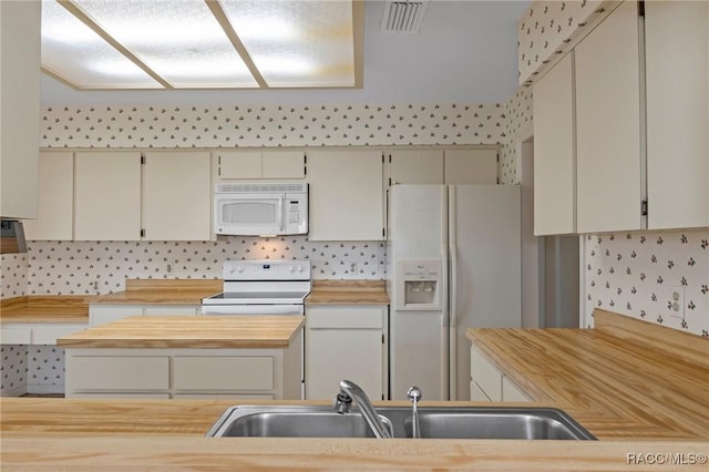 kitchen with tasteful backsplash, sink, white appliances, and butcher block countertops