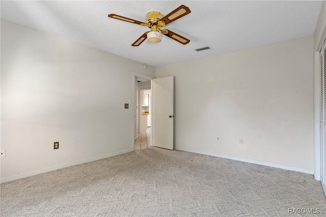 carpeted empty room featuring ceiling fan and a textured ceiling