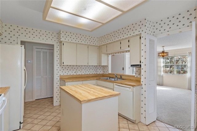 kitchen featuring white appliances, light carpet, wood counters, a kitchen island, and sink