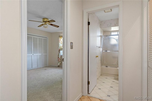 hall with light carpet and a textured ceiling