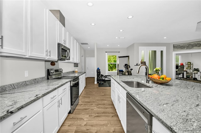 kitchen featuring white cabinetry, sink, light stone counters, light hardwood / wood-style flooring, and appliances with stainless steel finishes