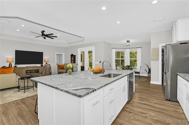 kitchen with a kitchen island with sink, sink, appliances with stainless steel finishes, and light hardwood / wood-style flooring