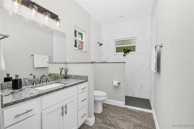 bathroom with vanity, toilet, and a tile shower