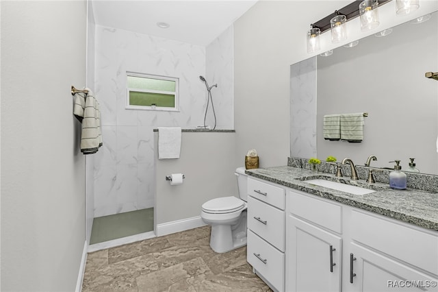 bathroom with vanity, toilet, and tiled shower