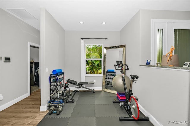 exercise room featuring hardwood / wood-style floors and independent washer and dryer